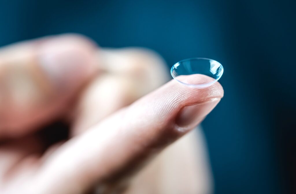 A close up of a person's hand holding a contact lens on their finger tip