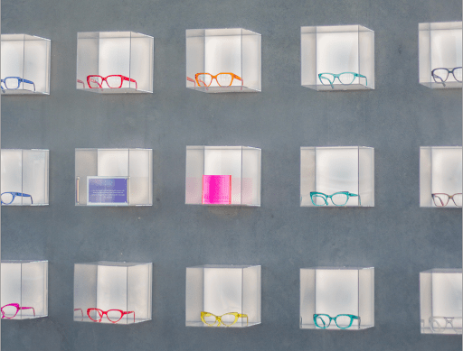 A display of eyeglasses of different colors and styles mounted on the wall of an optometry practice