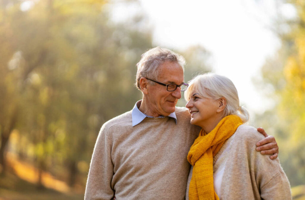 A senior couple smiling while on a walk through a forest area.