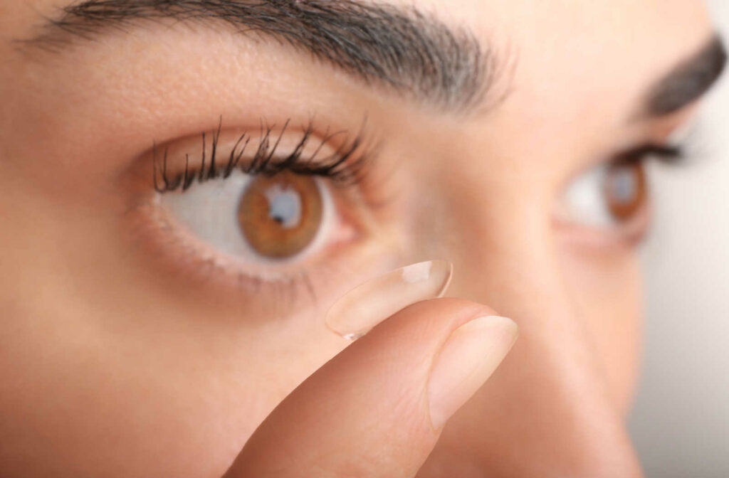 Close up shot of a female with a contact lens on her right pointing finger ready to be put in.