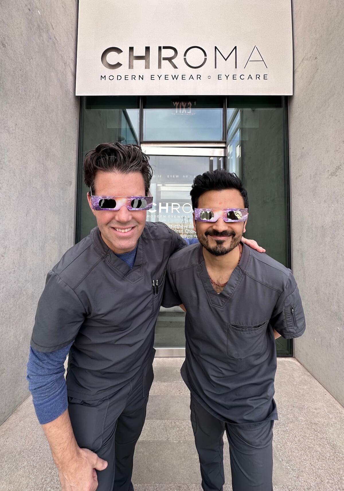 Dr. B and Dr. V wearing solar eclipse glasses outside of CHROMA.