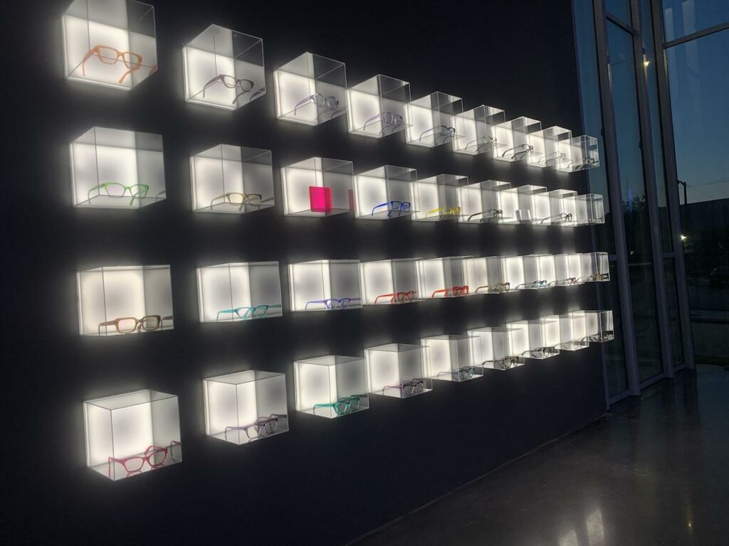 Illuminated eyewear display wall with colourful frames inside CHROMA modern Eyewear Eyecare.