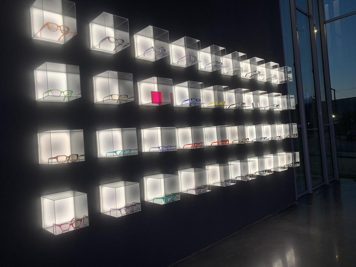 Illuminated eyewear display wall with colourful frames inside CHROMA modern Eyewear Eyecare.